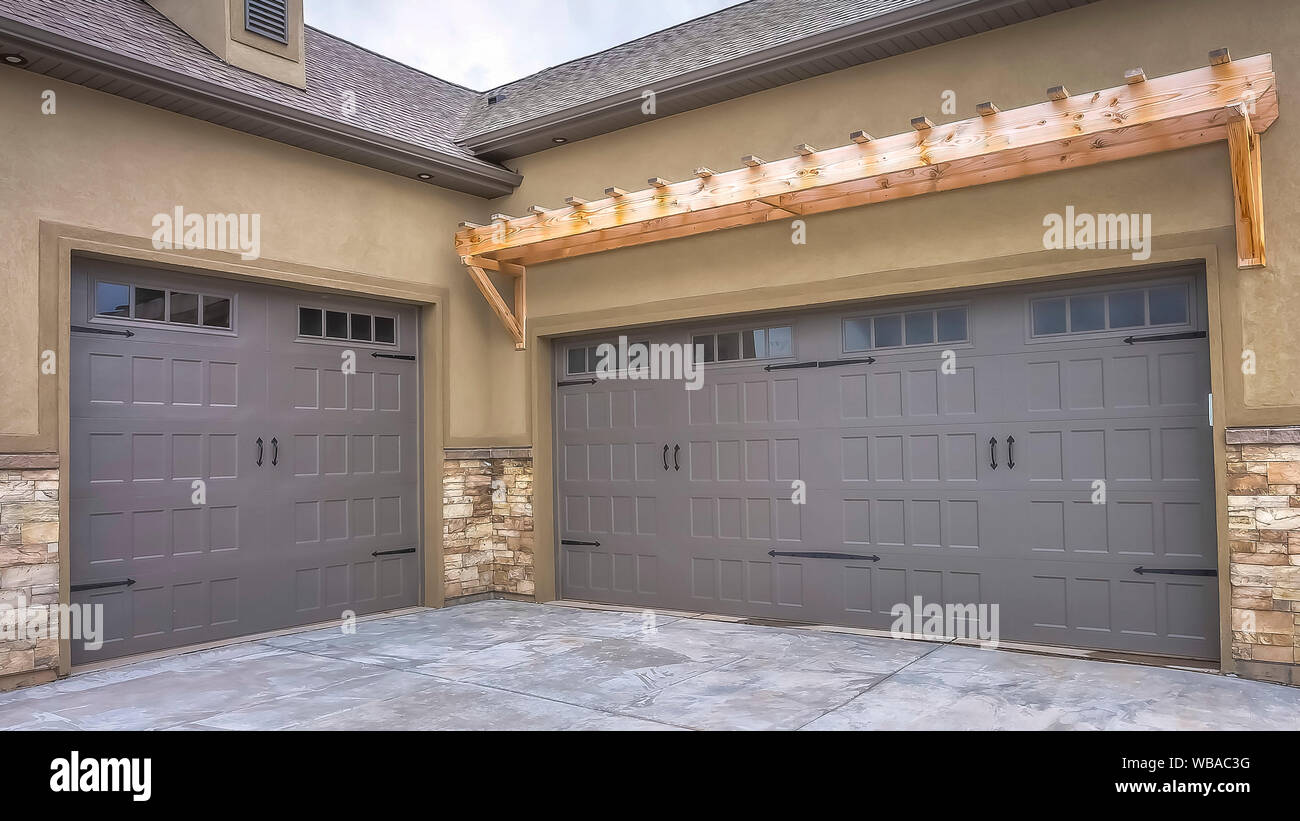 Panorama Exterior Of A Home With View Of Gray Double Garage Doors