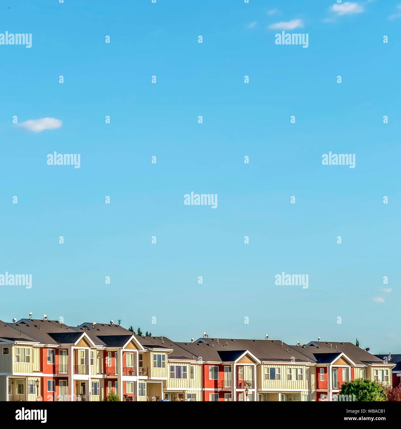 Square Blue sky on a sunny day over townhomes with white and red
