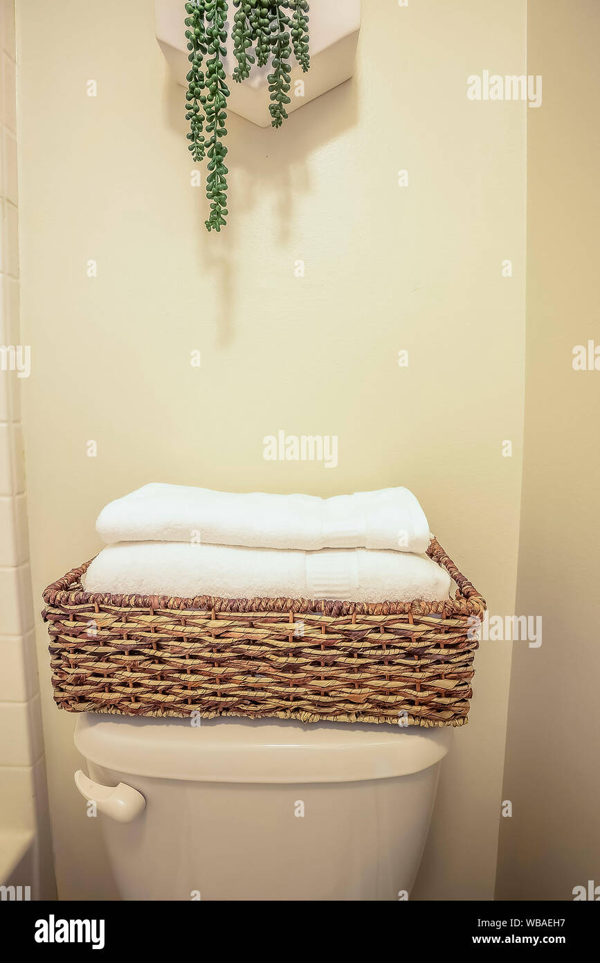 Folded towels inside a rattan bathroom tray placed on top of the toilet