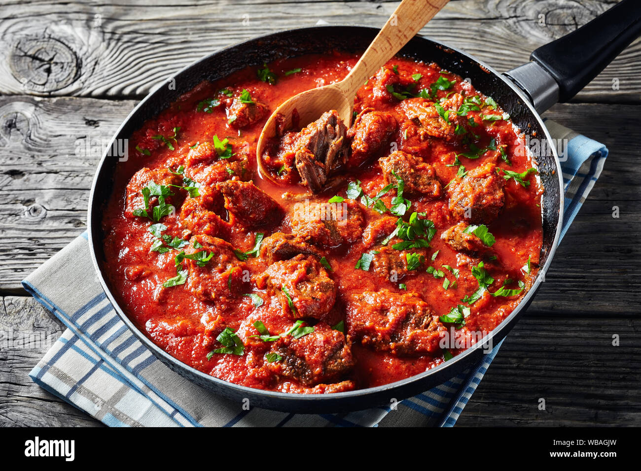 close-up of African Beef Stew in tomato sauce with spices and herbs in a skillet on an old wooden table, horizontal view from above Stock Photo