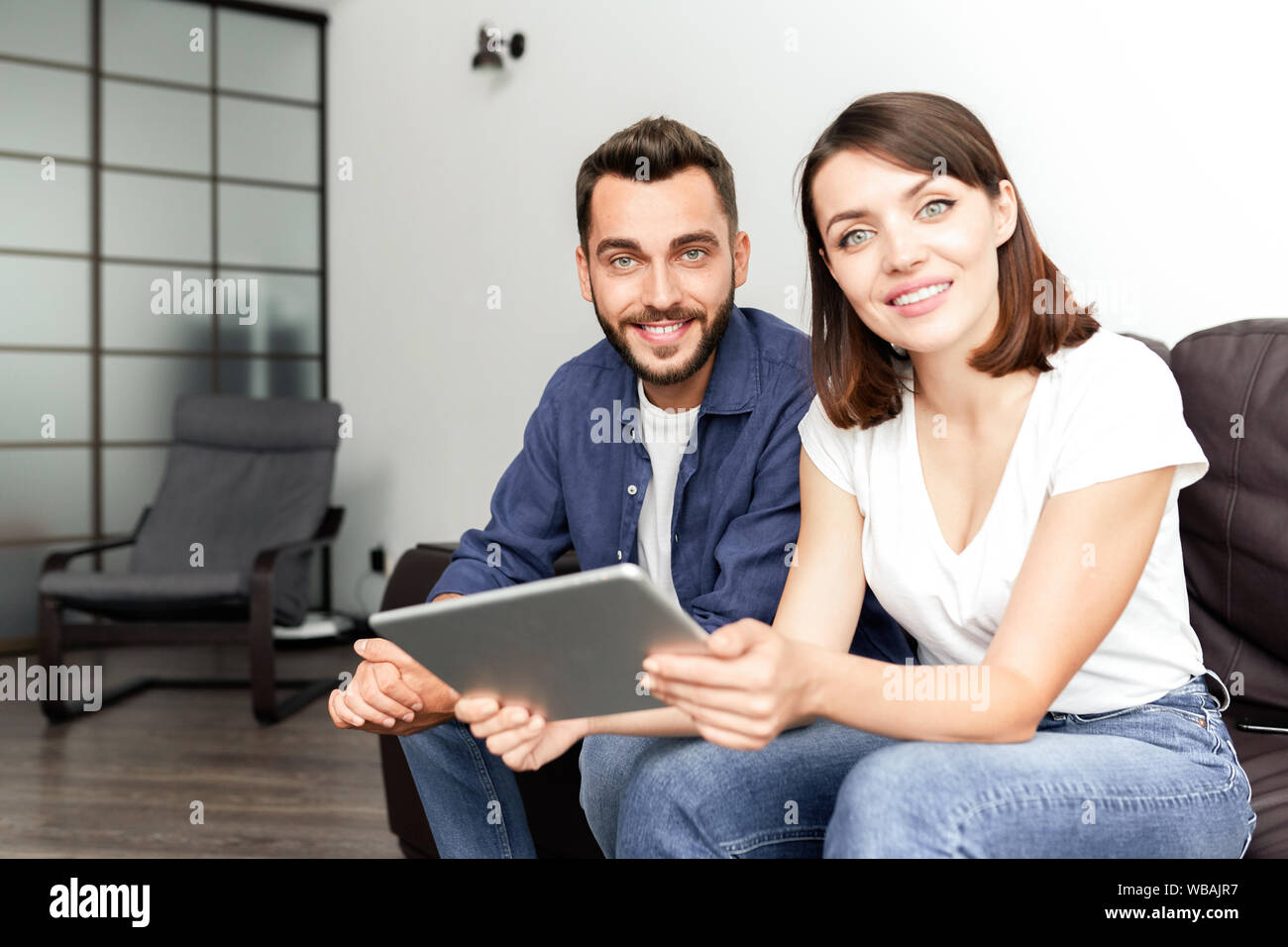 Positive couple using wifi at home Stock Photo