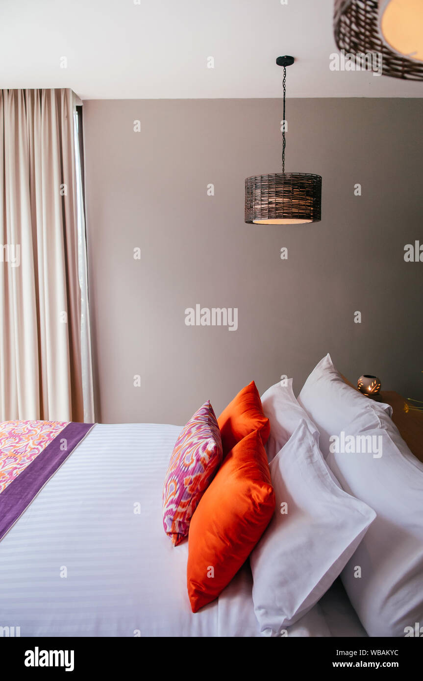 AUG 6, 2014 Hua Hin, THAILAND - Asian Thai tropical hotel room with bed and colourful pillows, rattan pedant lamps Stock Photo