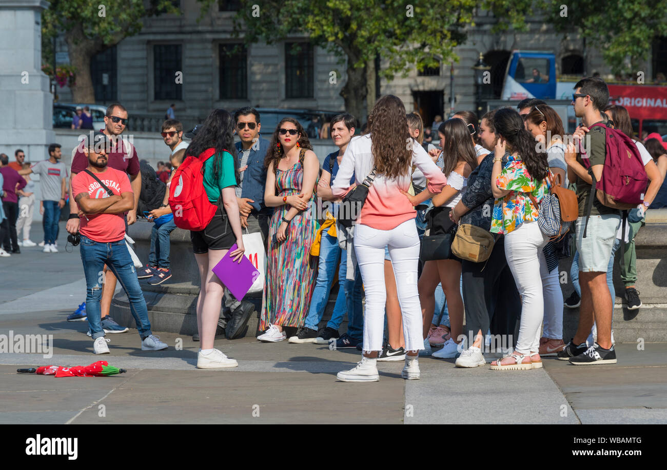 Group of tourists on a guided tour in Trafalgar Square, Charing Cross, City of Westminster, Central London, England, UK. Tour guide in London. Stock Photo