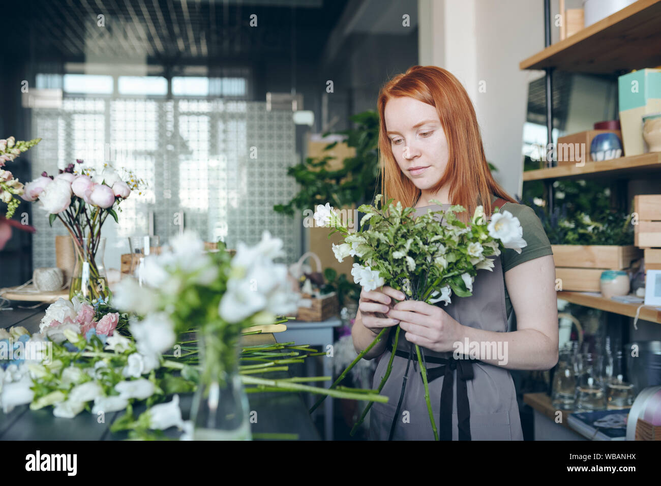 Young flower storekeeper making tender bouquet Stock Photo