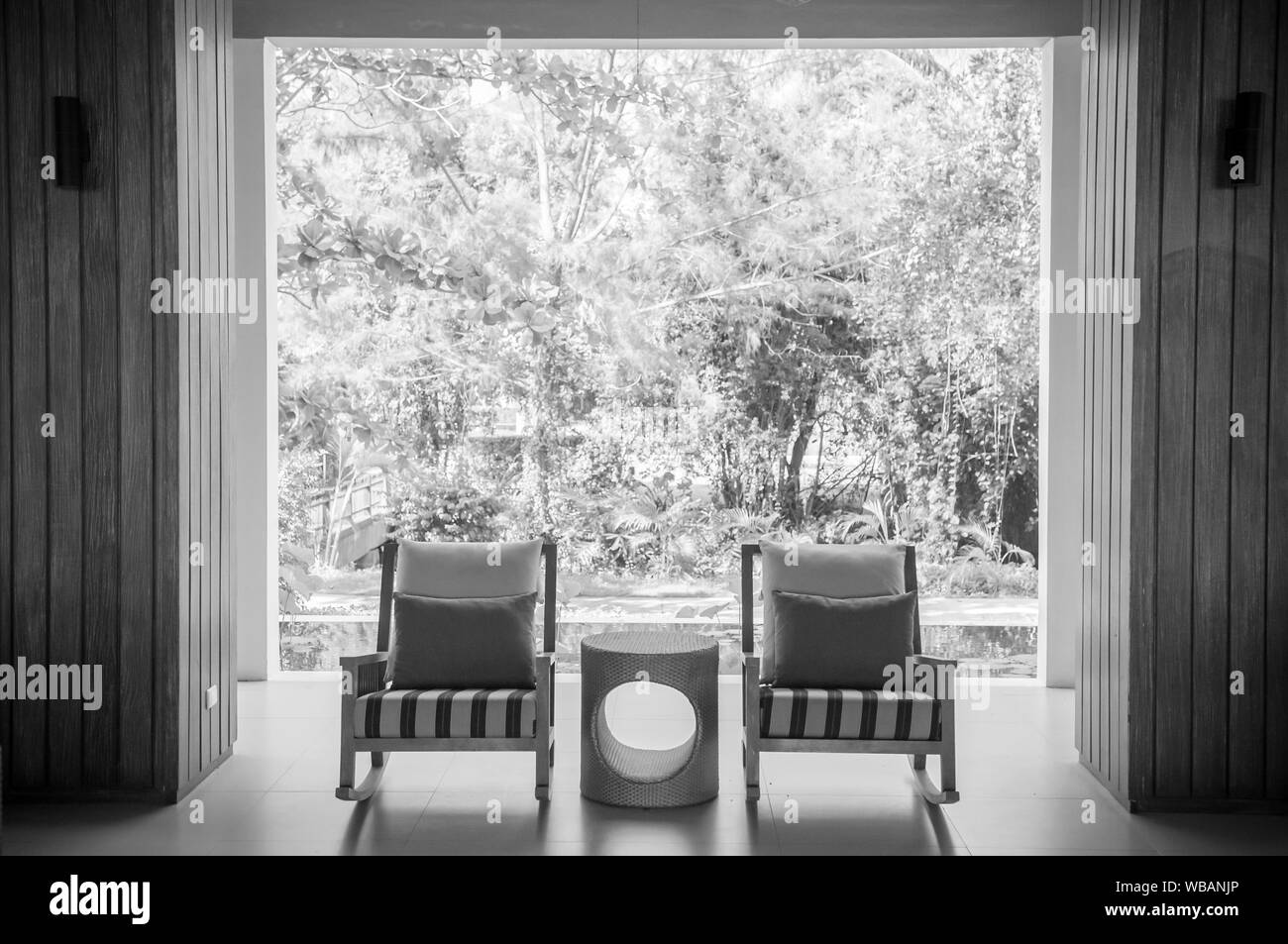 MAY 21, 2014 Krabi, THAILAND - Modern contemporary style rocking chairs with table garden view, pillows and minimal decoration. Black and white Stock Photo