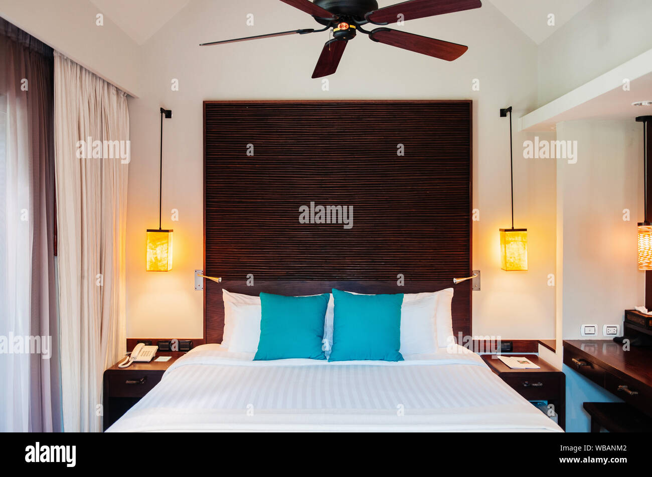 MAY 21, 2014 Krabi, THAILAND - Asian Thai tropical luxury resort room with wooden bed and white curtain, pedant lamps and ceiling fan. Contemporary ho Stock Photo
