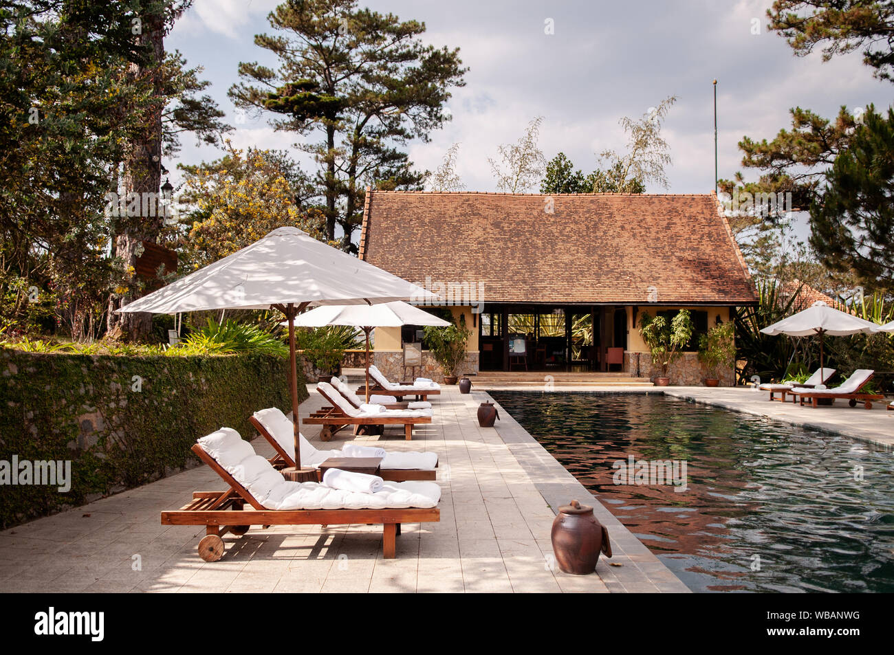 FEB 25, 2014 Dalat, Vietnam - Tropical Colonial resort style swimming pool in pine forest under evening sunlight in late winter with reflection on wat Stock Photo