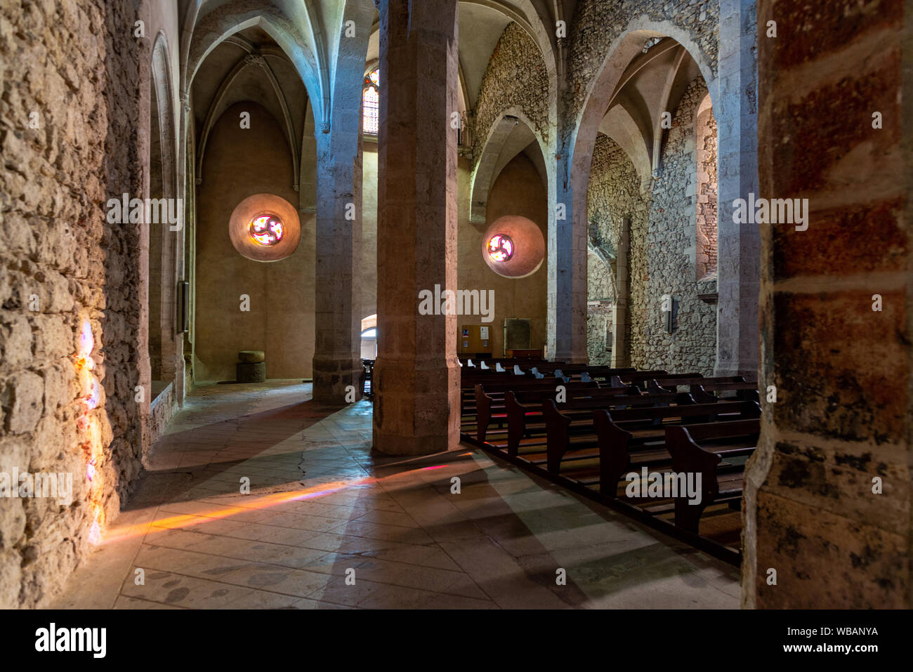 Church interior with colourful light from the stained glass, Perouges ...