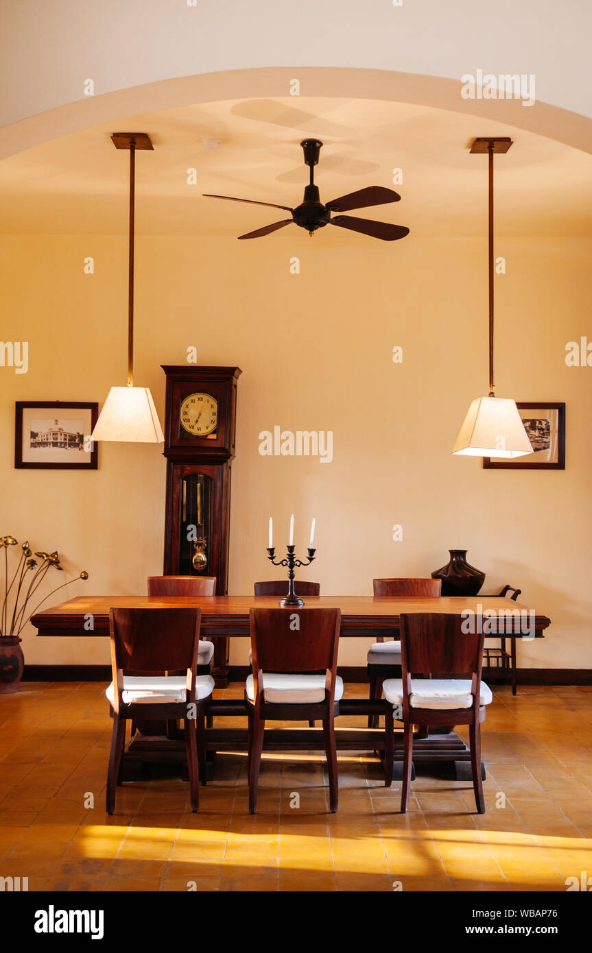 FEB 25, 2014 Dalat, Vietnam - Vintage ceramic tile floor dinner room with hard wood table, chair, white curtain, classic pedant lamps and Asian style Stock Photo