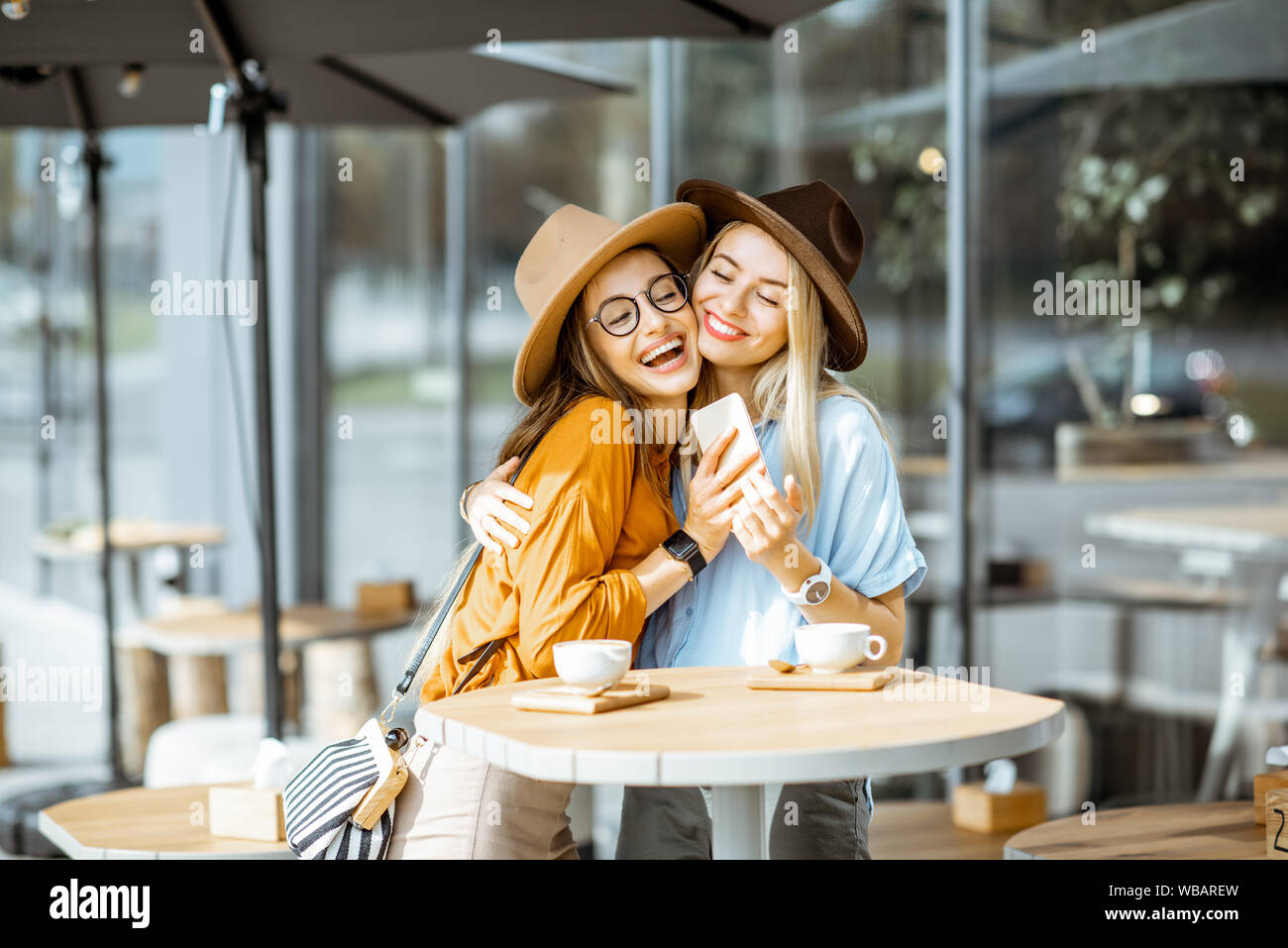 Meeting of a two female best friends at the cafe outdoors, hugging ...