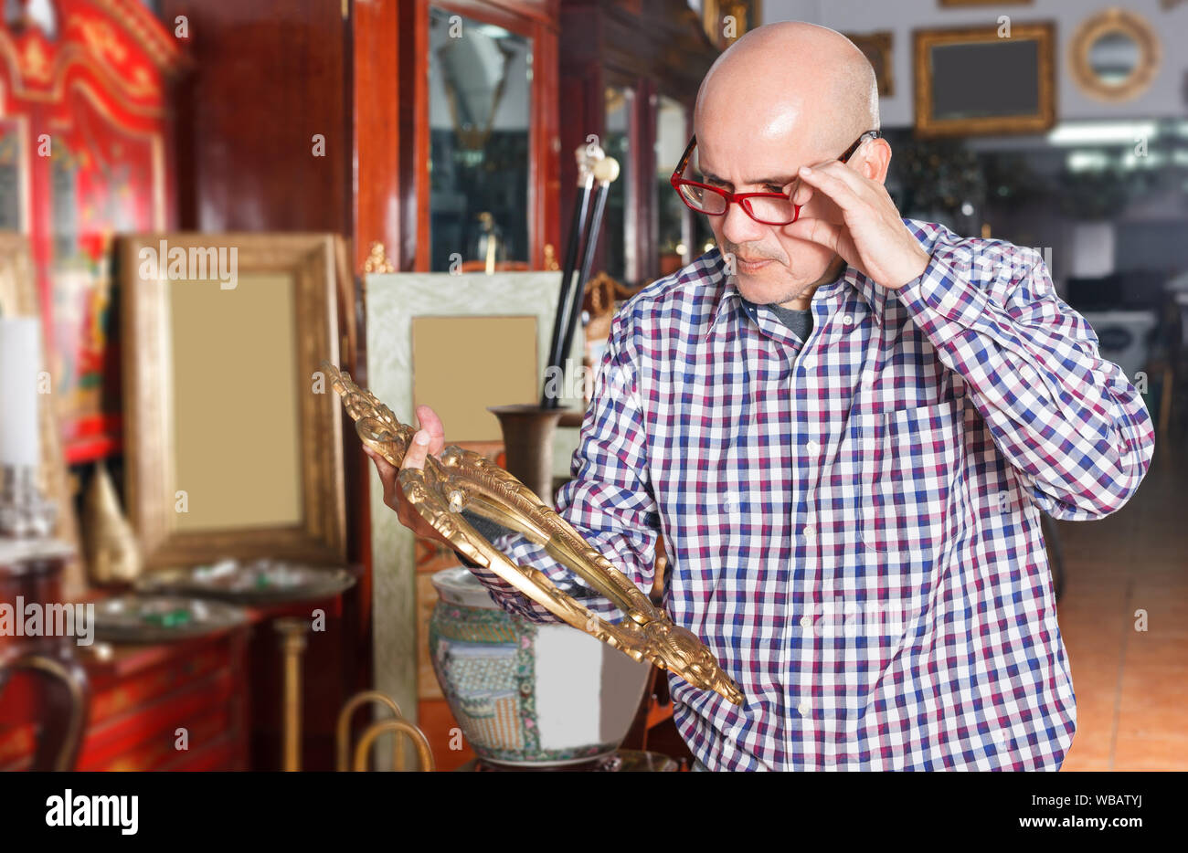 happy adult man visiting shop of antique goods in search of interesting objects Stock Photo