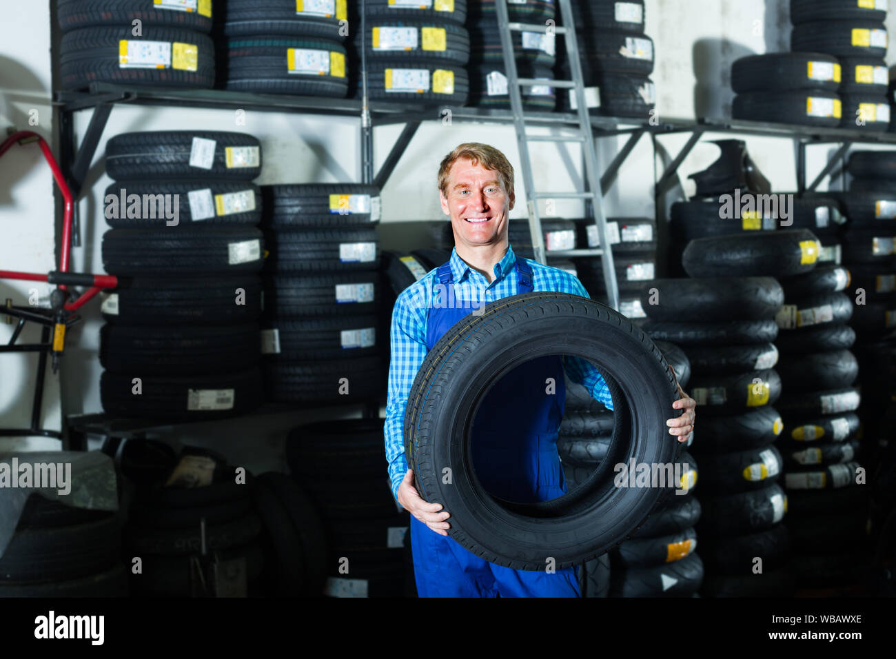 Technician man working with new tyre for car in tire shop Stock Photo