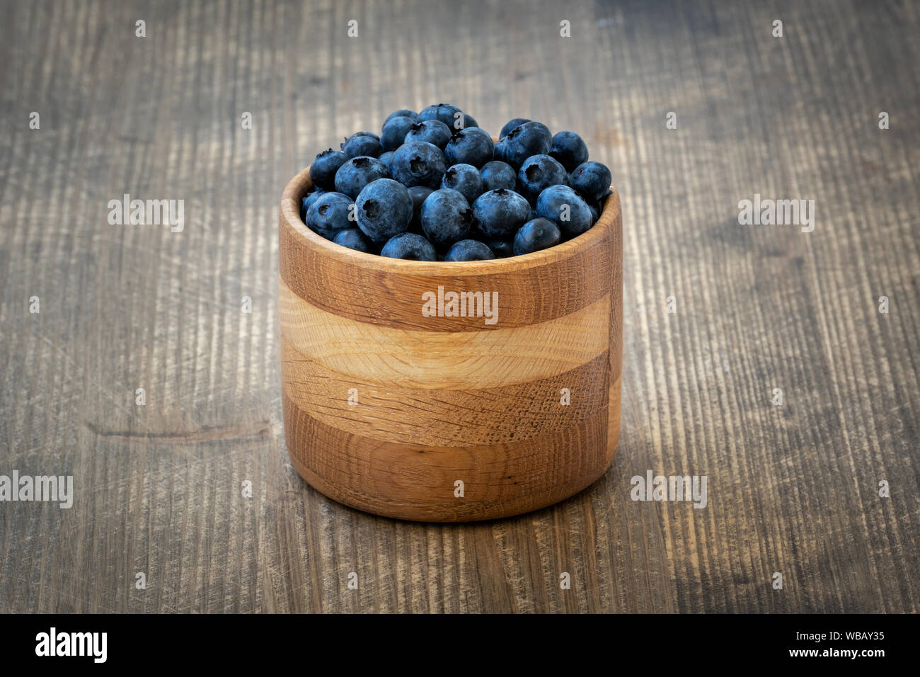 Freshly picked blueberries in wooden bowl on wooden background. Healthy eating and nutrition. Stock Photo