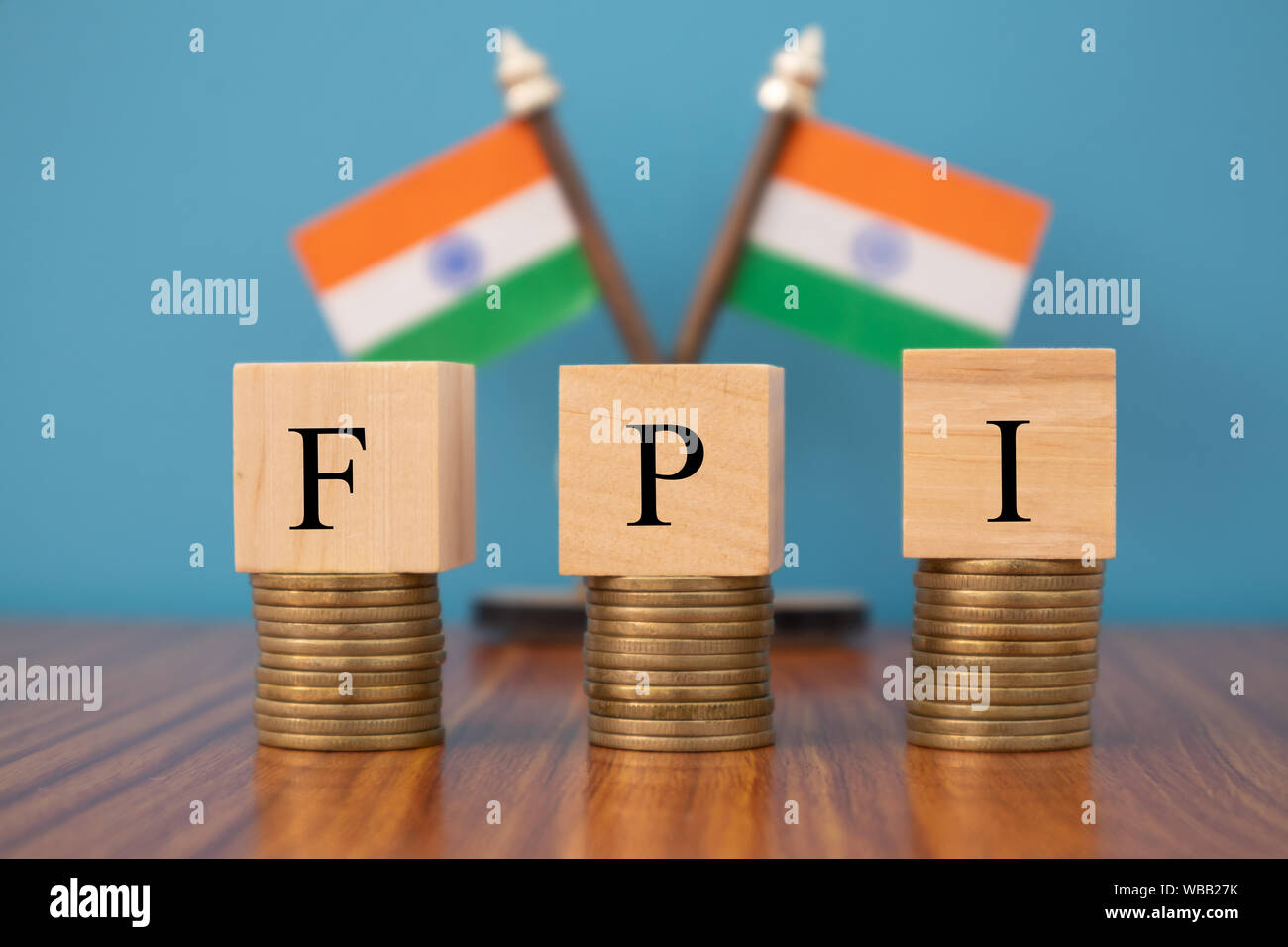 Concept of FPI or foreign portfolio investment on India in wooden block letters on stack of coins with Indian Flag as a background. Stock Photo