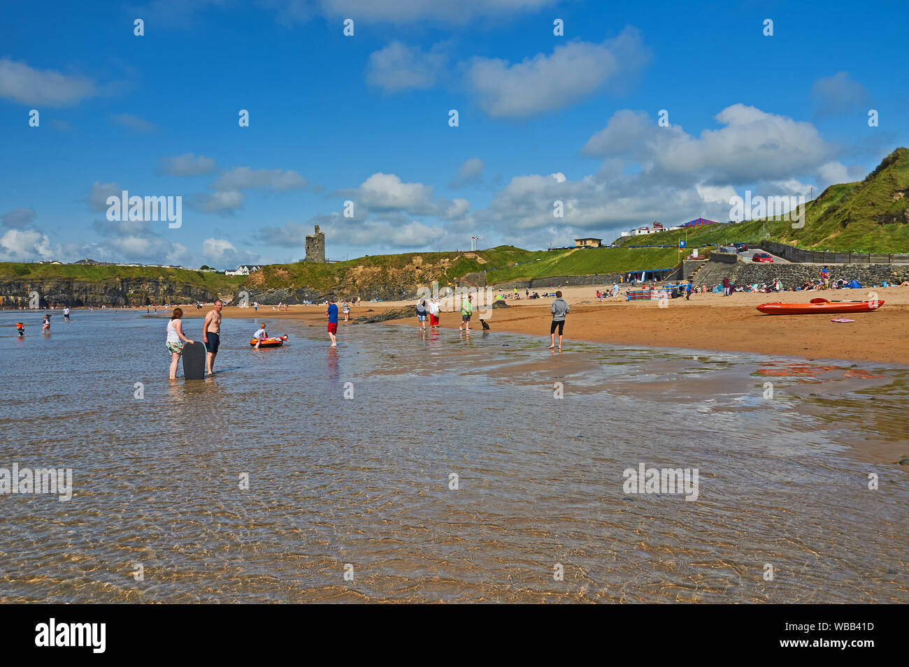 Ballybunion beach on the Atlantic Coast, with tourists and locals paddling in the shallow surf of a calm Atlantic Ocean, County Kerry, Ireland. Stock Photo