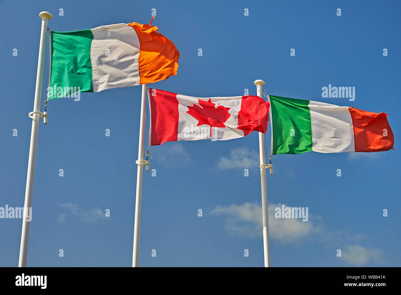 The flags of Italy, Canada and Republic of Ireland (Eire)flying on flagpoles against a blue sky. Stock Photo