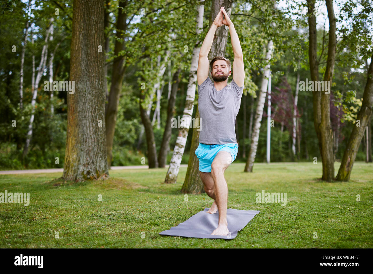 Focused young man doing yoga pose in the park in the morning Stock Photo