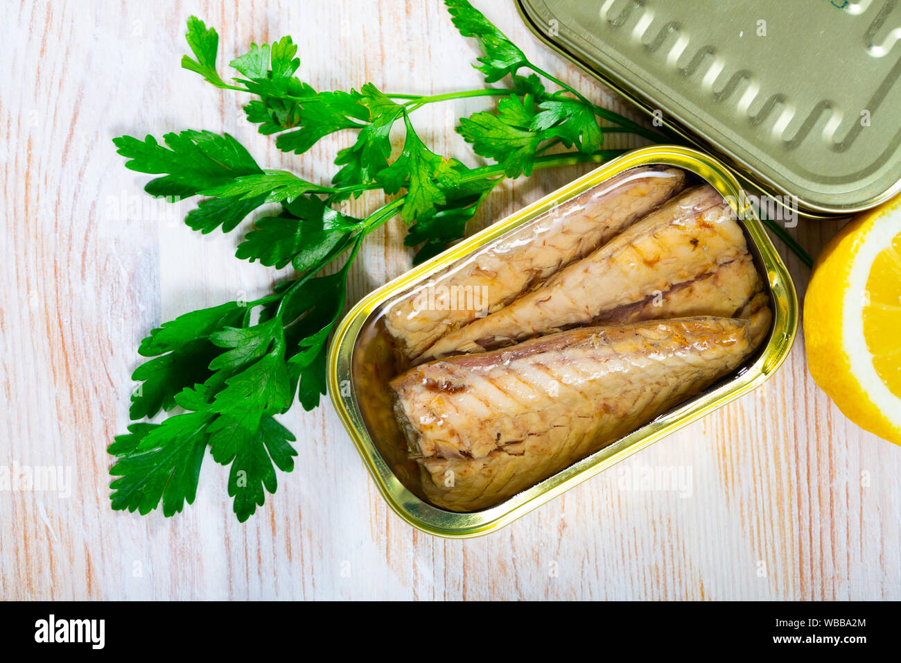Picture of  tasty  fillet of mackerel  in sunflower oil with greens and lemon at table Stock Photo