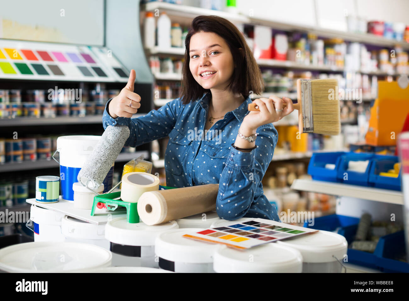 Woman 20-24 years old is purchasing tools for house improvements in paint supplies store. Stock Photo