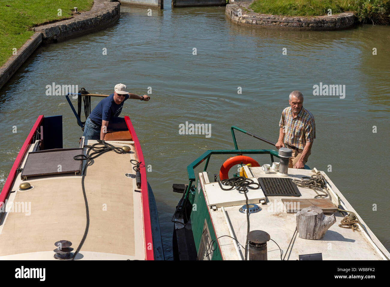 Devizes, Wiltshire, England, UK. August 2019.  Two narrowboat skippers holding the tillers of their boats as they enter a lock on the Kennet and Avon Stock Photo