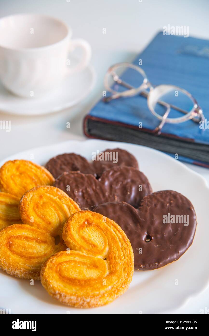 Pastries called palmeras, cup, eyeglasses and agenda. Still life. Stock Photo