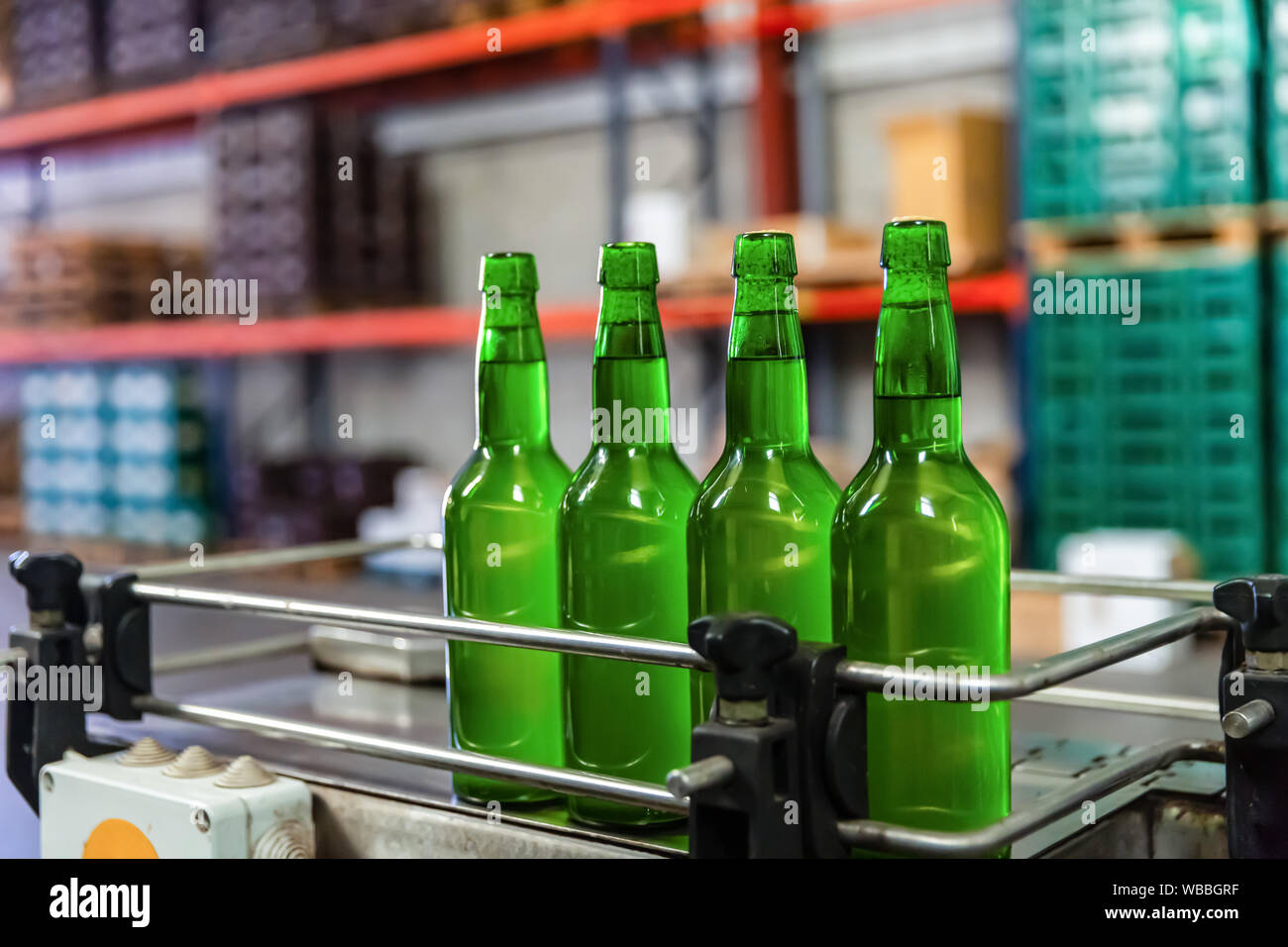 Four green glass bottles of apple cider on bottling line at factory Stock Photo
