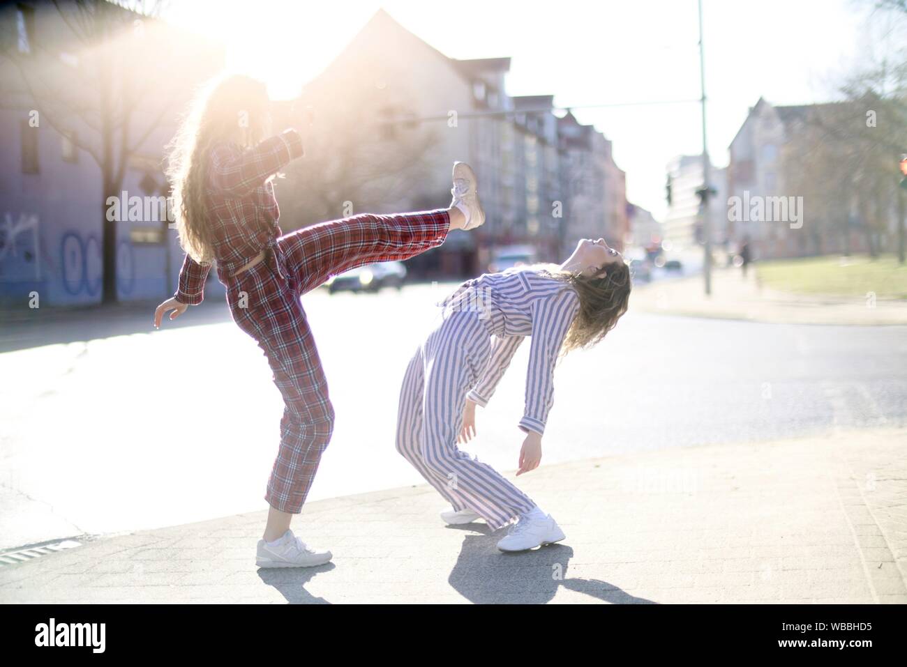 two young women fighting at street, wearing pyjamas, roundhouse kick ...