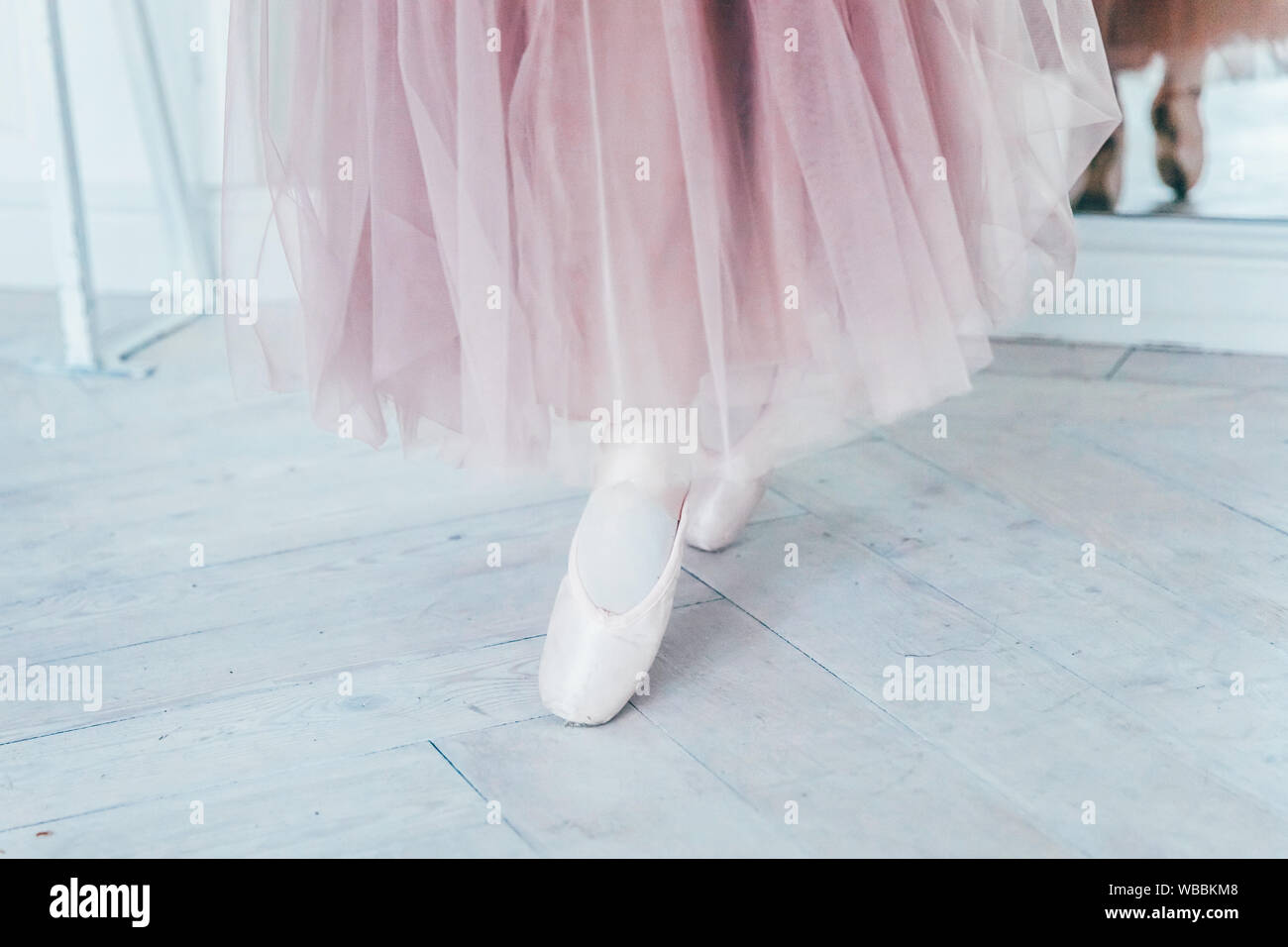 Hands of ballerina in pink tutu skirt puts on pointe shoes on leg in ...