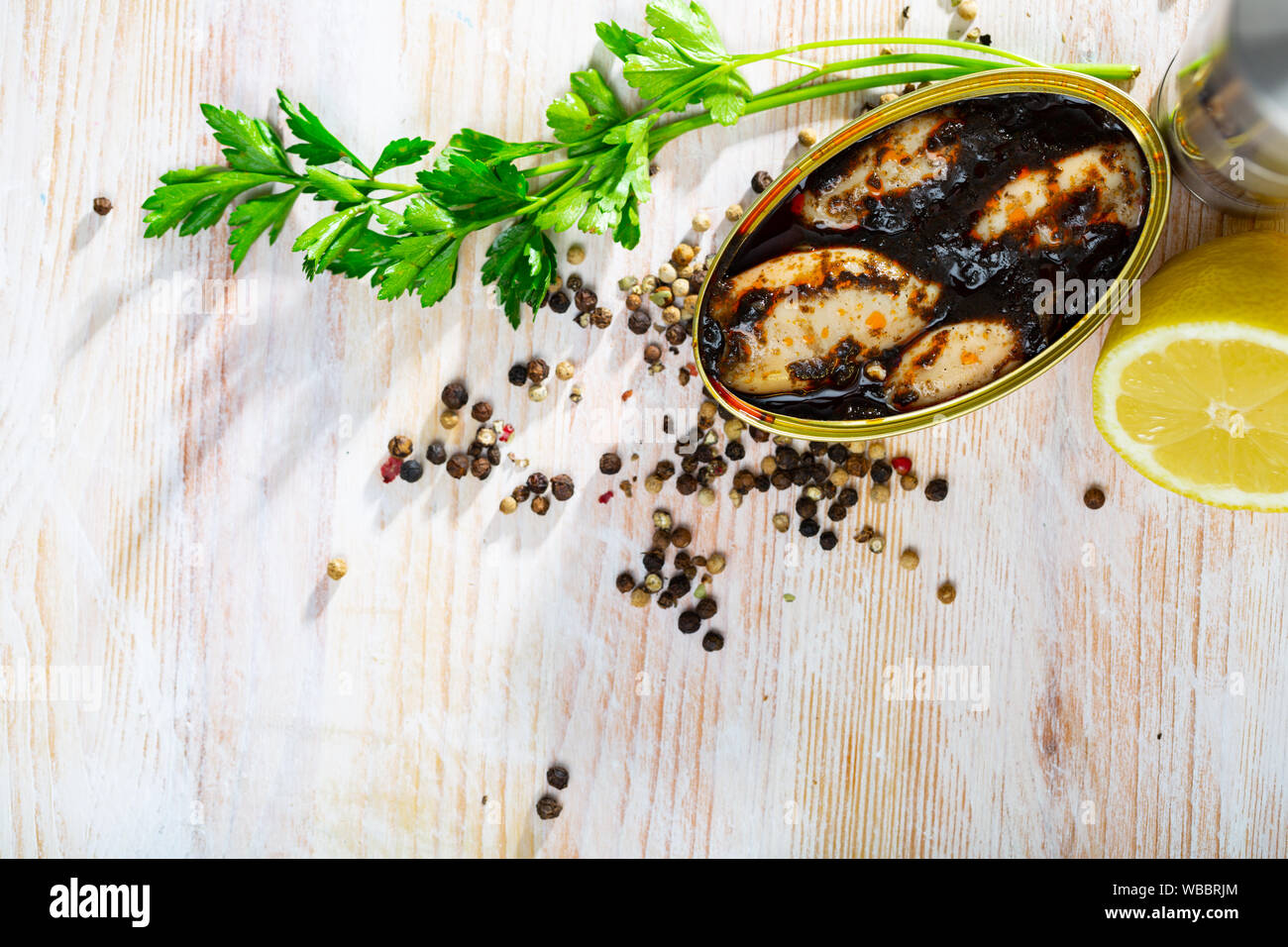 Open can with stuffed whole squid in ink sauce preserves on wooden table Stock Photo