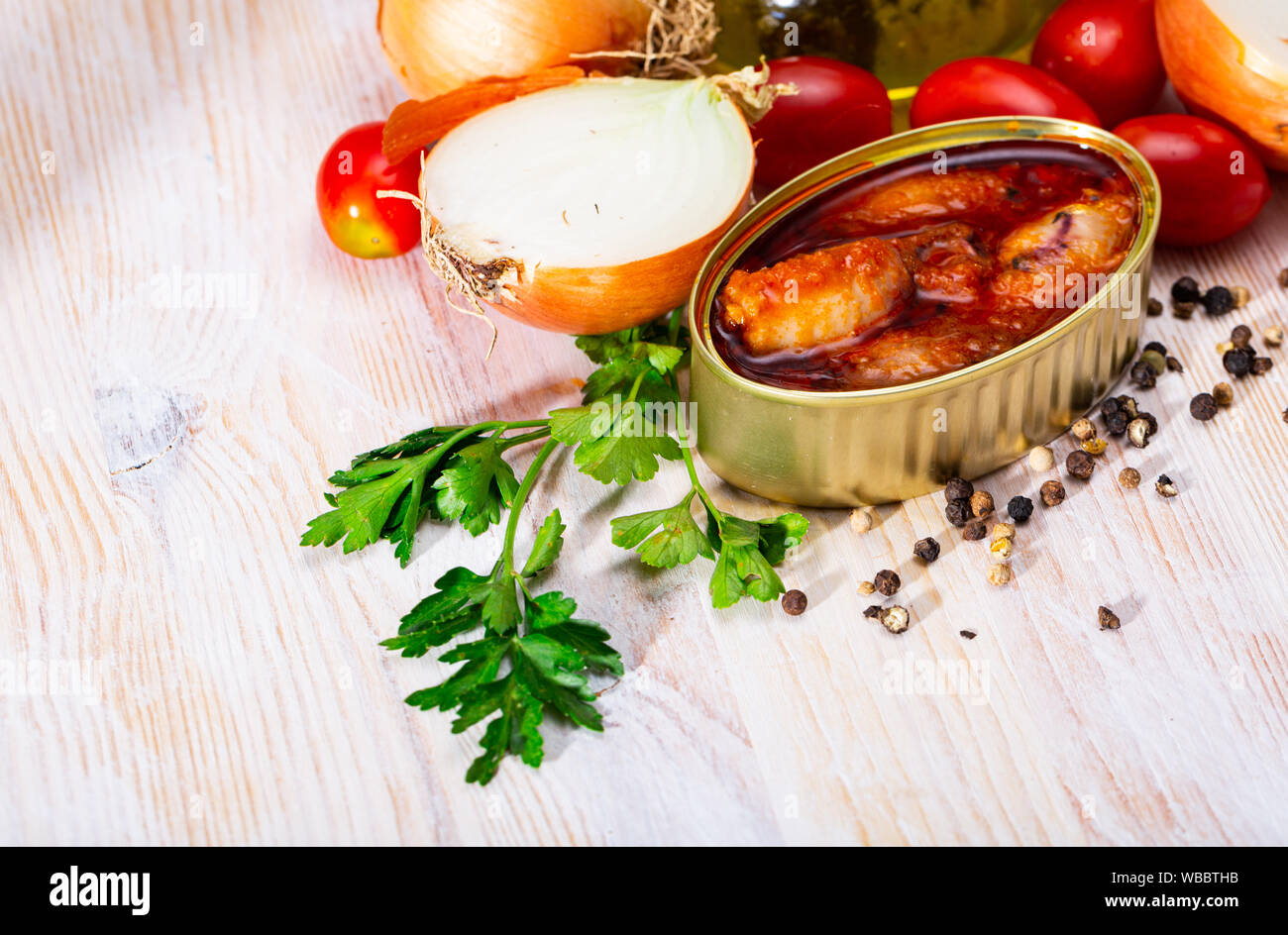 Picture of  tasty stuffed squid in tomato sauce on background with greens, tomatoes and onion Stock Photo