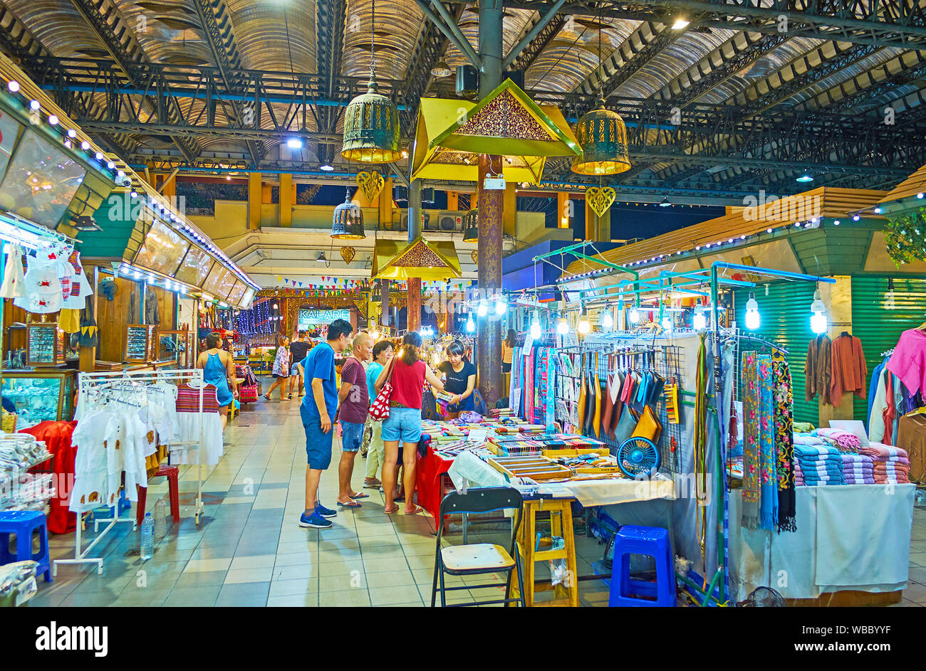 CHIANG MAI, THAILAND - MAY 2, 2019: People choose interesting pieces of clothes and accessories in stalls of Night Bazaar shopping center, on May 2 in Stock Photo