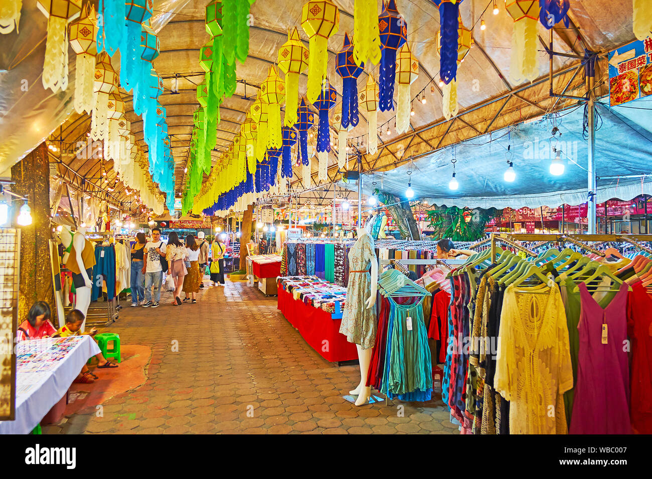 CHIANG MAI, THAILAND - MAY 2, 2019: The long alley of clothes section of Kalare Night Market with stalls, stretching along the tent, that is decorated Stock Photo