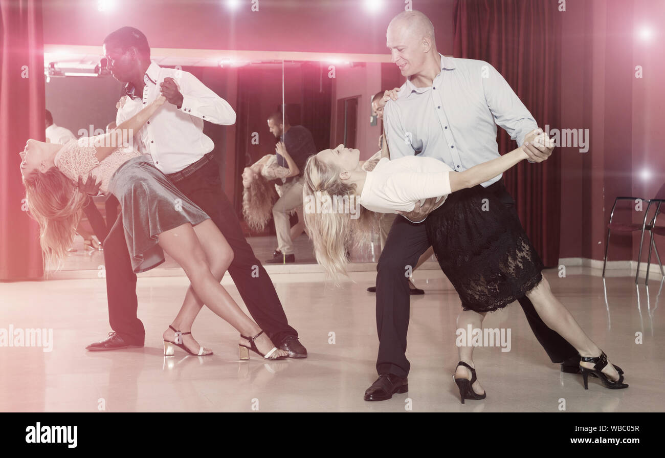 Young smiling people practicing passionate samba in dance class Stock Photo
