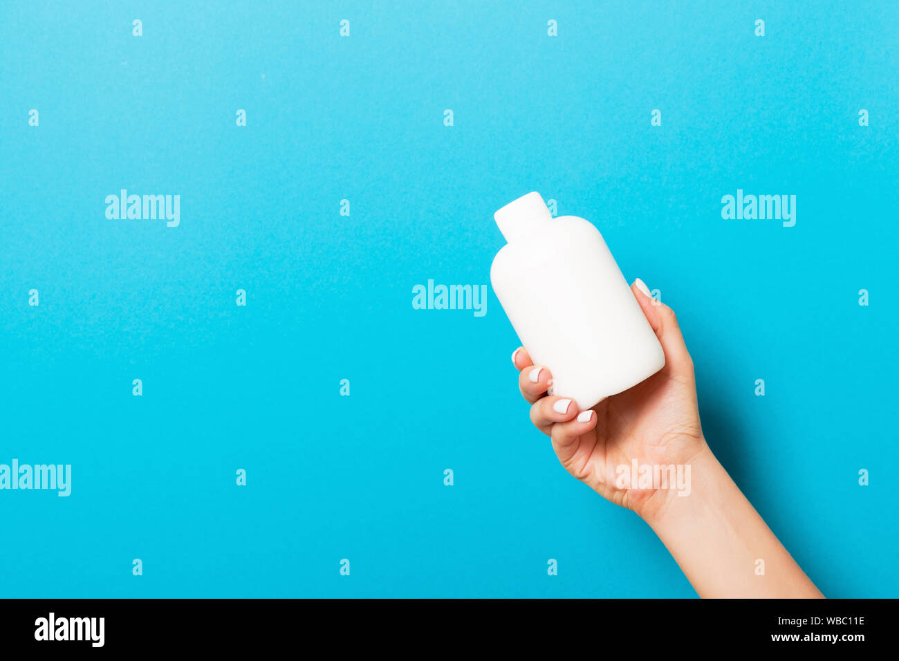 Female hand holding cream bottle of lotion isolated. Girl give tube