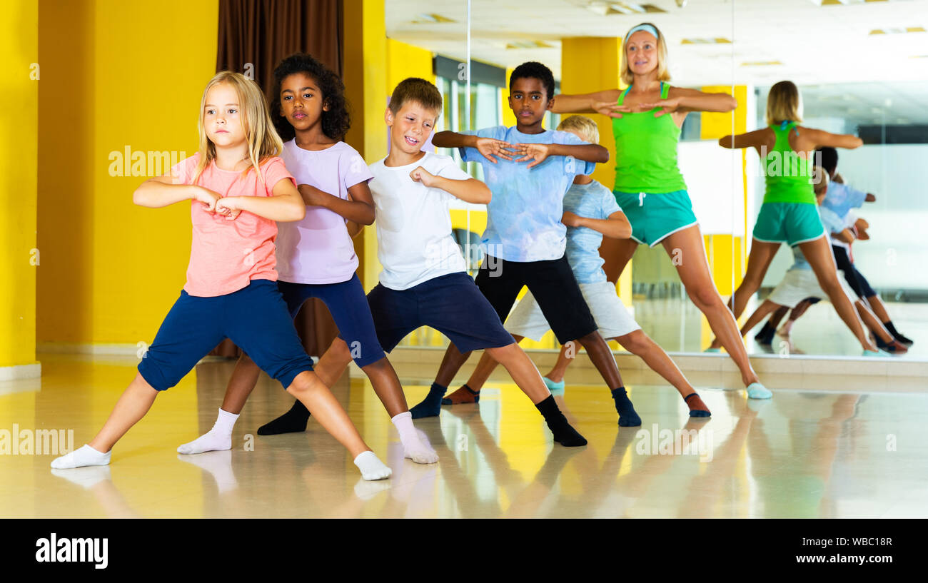 Group of preteen boys and girls training movements of modern dance in