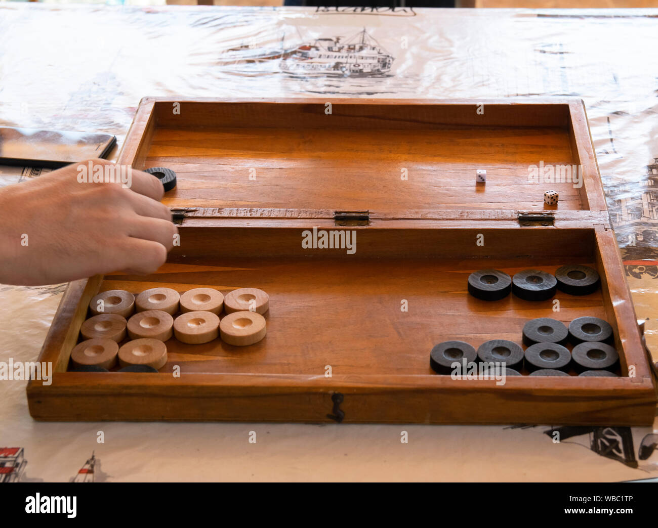 Playing backgammon on a wooden table with dices. Stock Photo