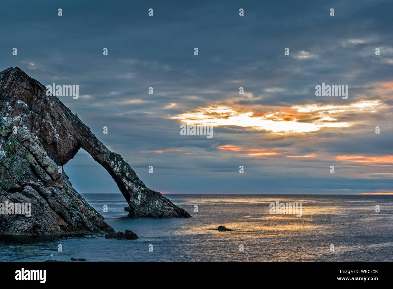 BOW FIDDLE ROCK PORTKNOCKIE MORAY SCOTLAND A GREY CLOUD SUNRISE WITH GOLDEN LIGHTS SUMMER MIDAUGUST Stock Photo