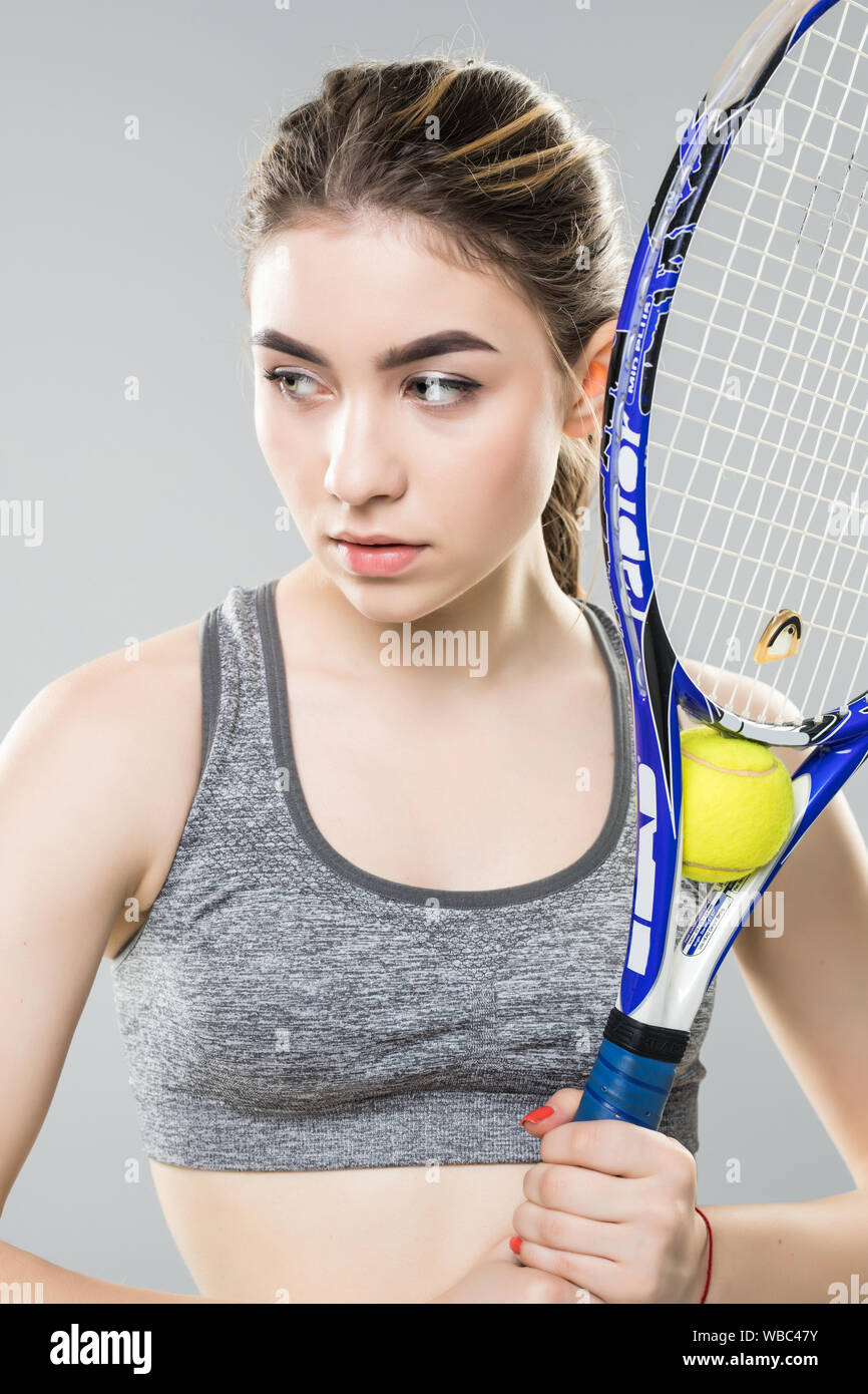 Woman with a tennis racket over her face. Neutral face and confident look.  Close up shot, sport portrait on black Stock Photo - Alamy