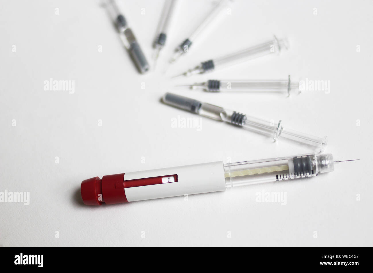 Assisted reproductive technology injection pen and small syringes with ovarian ultrasound in the middle. IVF and IUI Treatment Drugs. Stock Photo