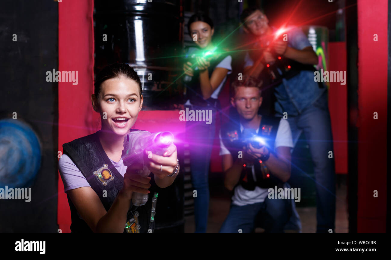 Happy girl with laser guns took aim and having fun with friends during laser tag game Stock