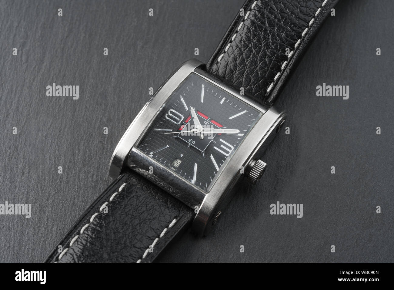 Elegant expensive square shaped wrist watch with black leather strap on a stone slate plate background Stock Photo Alamy