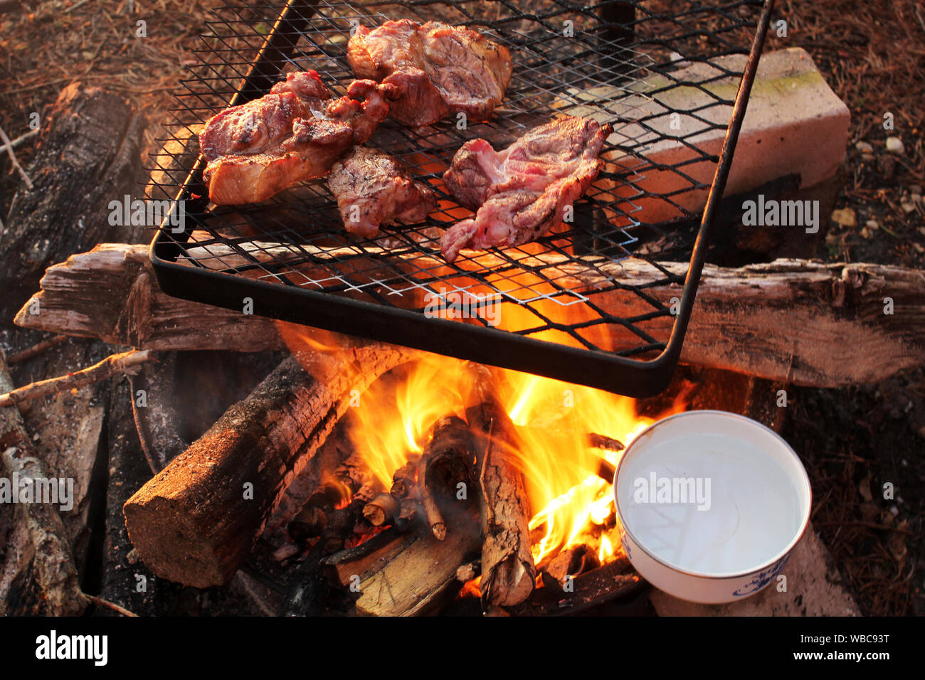 grilling meat and boiling eggs on campfire Stock Photo