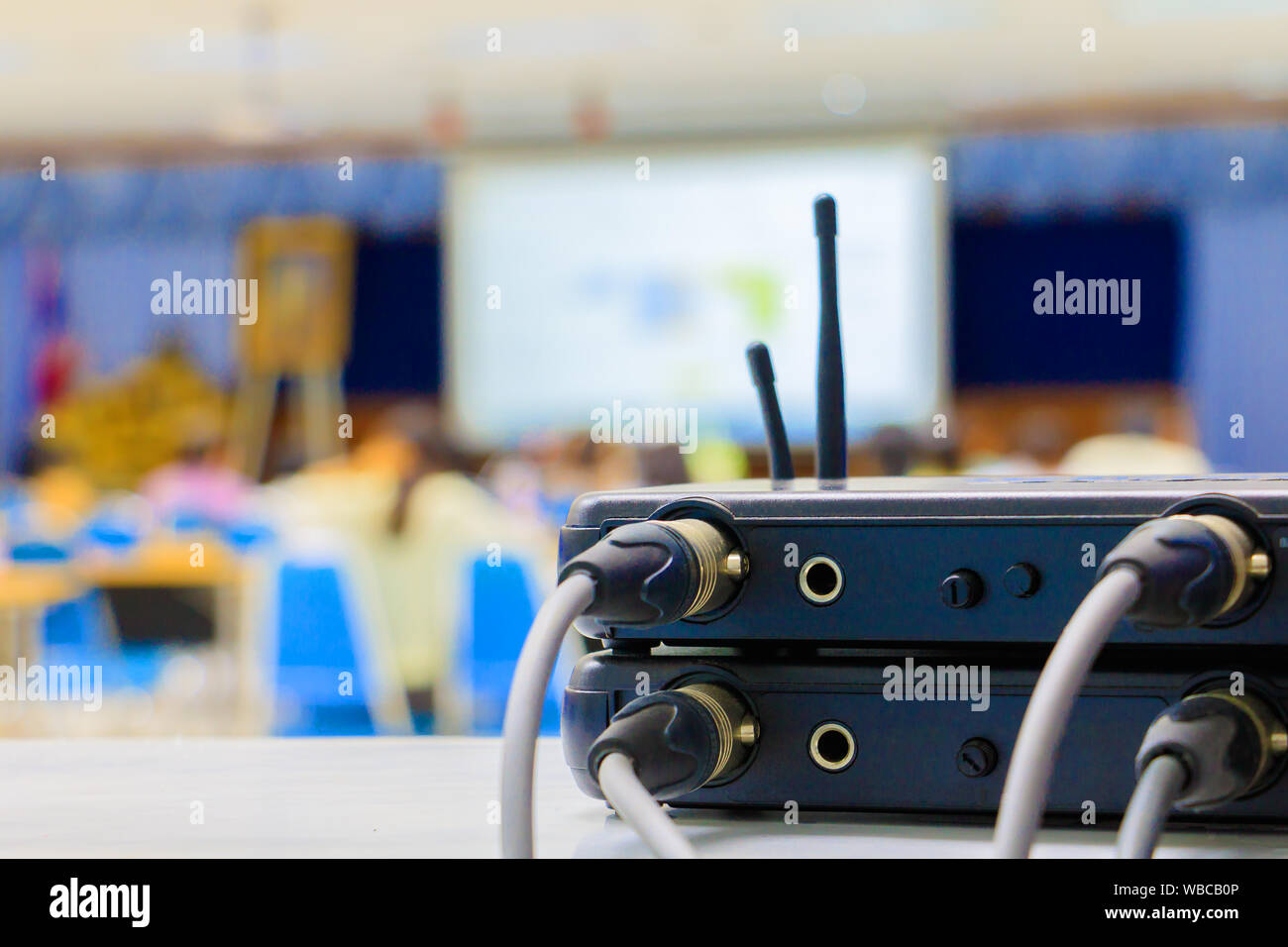 Close up Jack plug cables connected with old box of wireless microphone in conference meeting room seminar business blur. Stock Photo