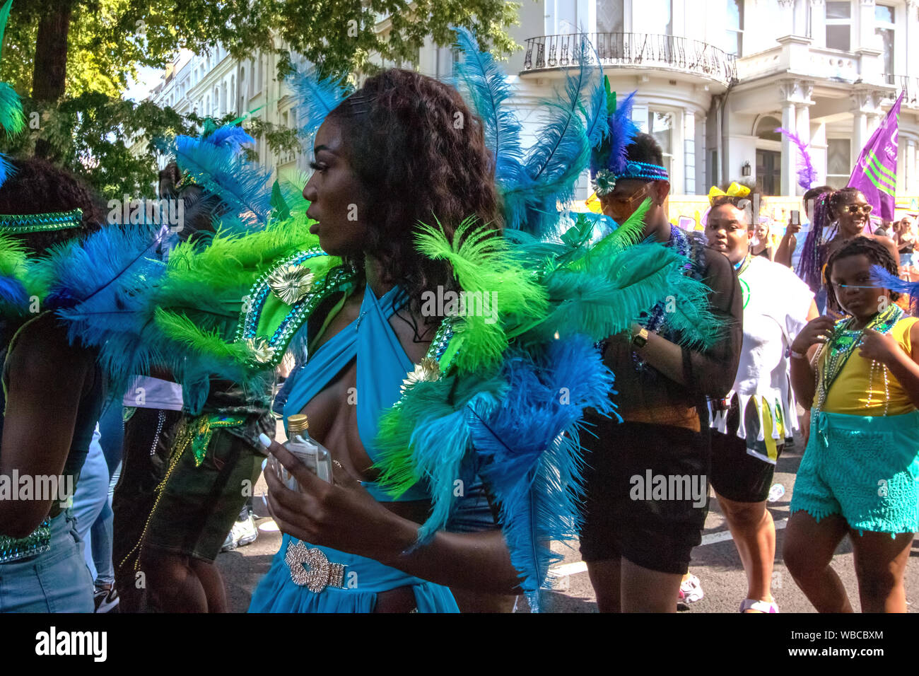 Masqueraders behind a truck. The main events of Notting Hill Carnival 2019 got underway on Sunday, with over a million revellers hitting the streets of West London, amongst floats, masqueraders, steel bands, and sound systems. Stock Photo