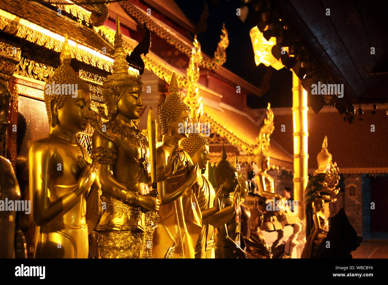 Golden Buddha statues at night in temple in Thailand, Chiang Mai Stock Photo