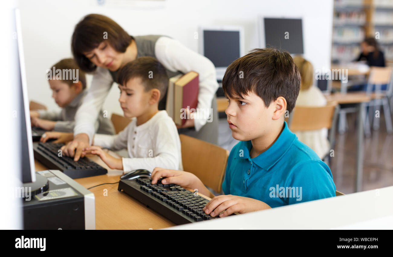 Focused boy studying in computer class of school library on background with  classmates and teacher Stock Photo - Alamy