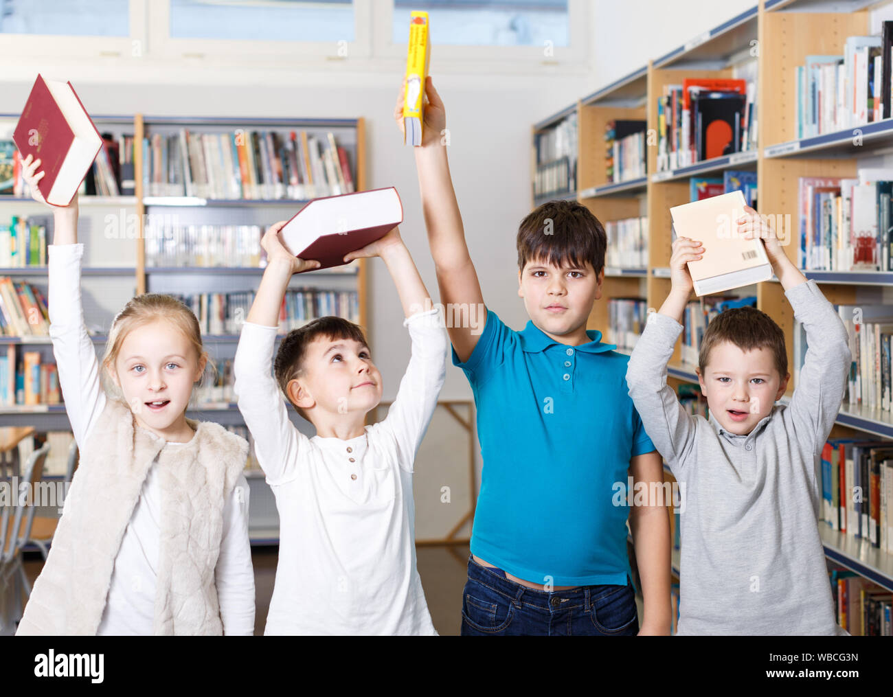 Group portrait of happy children standing with books in hands in modern school library Stock Photo