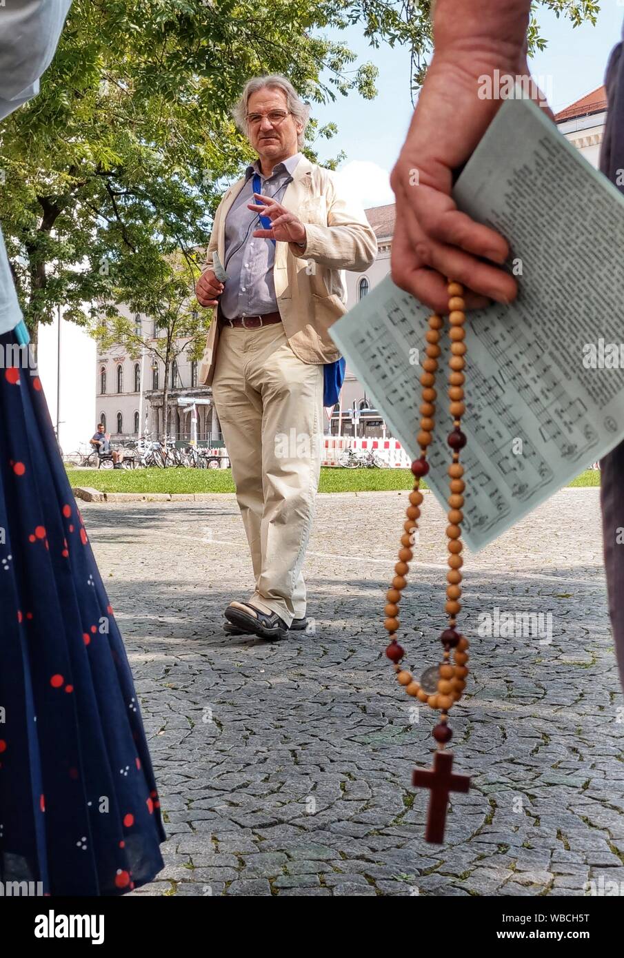 Munich, Bavaria, Germany. 26th Aug, 2019. Anti-abortion activist WOLFGANG HERRING holds a vigil with rosary beads visible in the foreground. Headed by well-known anti abortion activist Wolfgang Herring, a small group of Christian anti-abortion activists marched through the city of Munich, protesting against the Pro Familia organization who offers counseling services for pregnant women, ultimately ending at the Ludwig Maximilian University's Geschwister Scholl Platz. Credit: Sachelle Babbar/ZUMA Wire/Alamy Live News Stock Photo