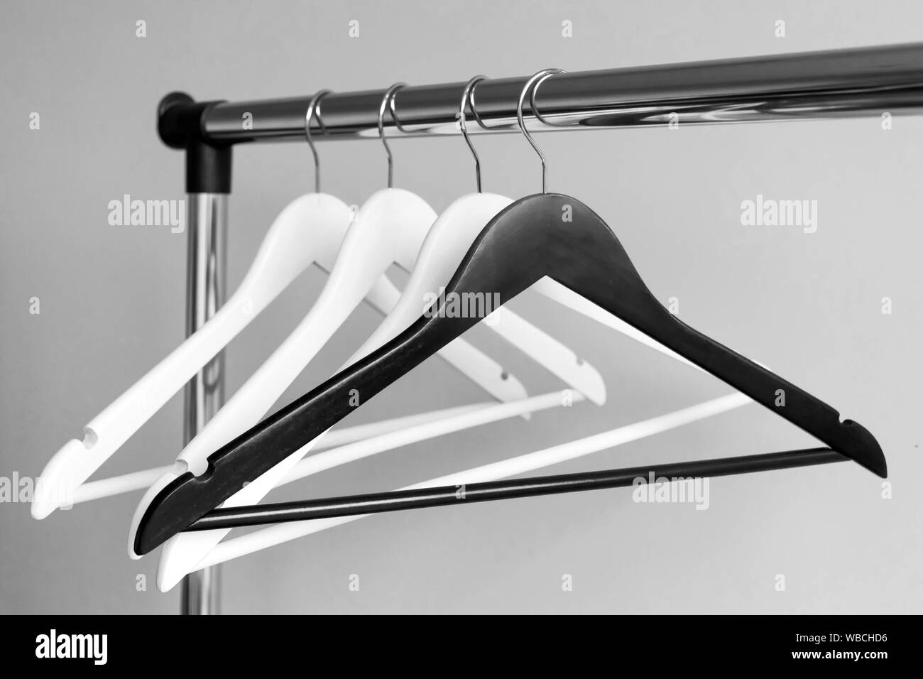 Empty clothes hangers on metal rail against grey background