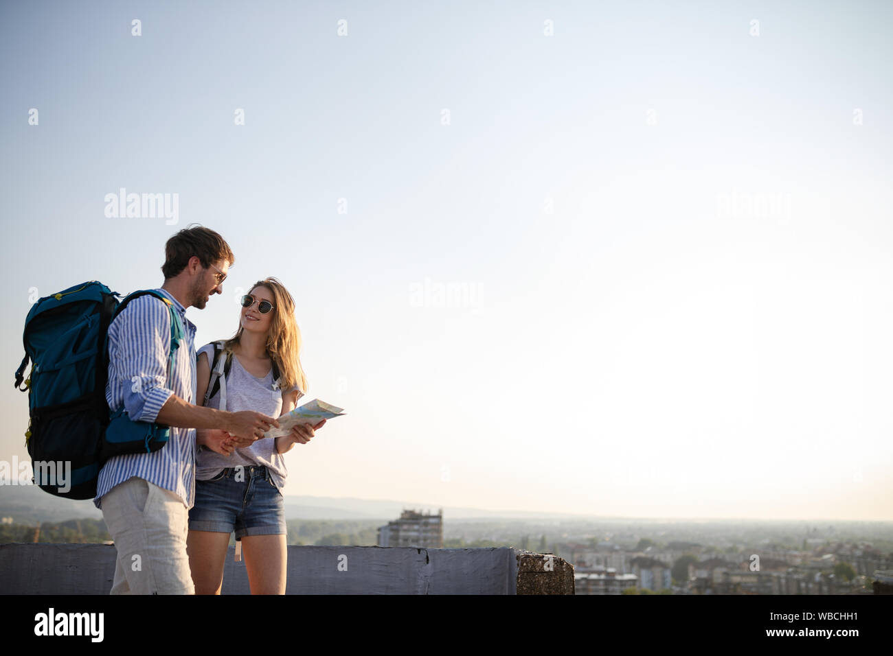 Happy young couple of travellers holding map in hands Stock Photo